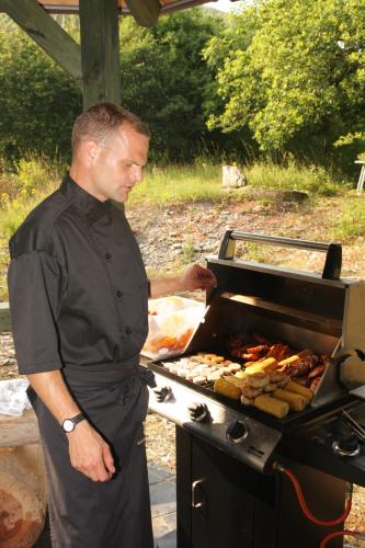 a man is cooking food on a grill at Weinhaus Burg-Schneider in Reil