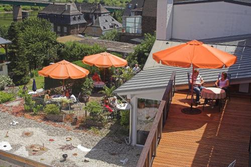 an outdoor deck with orange umbrellas and people sitting at Weinhaus Burg-Schneider in Reil