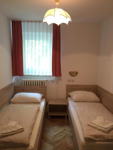 two beds in a room with a window and a chandelier at Apartmaji in sobe Tina in Kranjska Gora