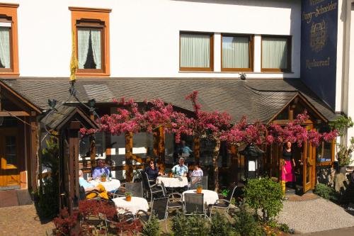 a group of people sitting at tables in front of a building at Weinhaus Burg-Schneider in Reil