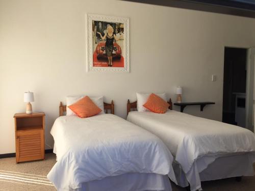 Duas camas num quarto com uma fotografia na parede em Pearl Oyster guesthouse em St Francis Bay