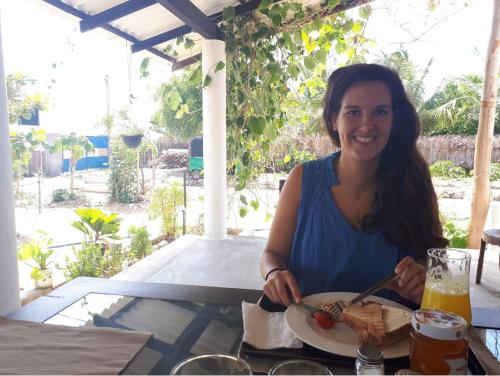 a woman sitting at a table with a plate of food at De Perla Resort in Arugam Bay