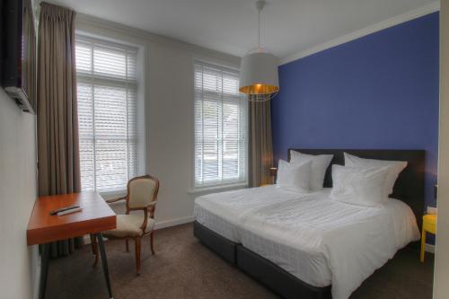 a bedroom with a bed and a table and a desk at Hotel In't Holt 1654 Grand Café & Logement in Zuidhorn