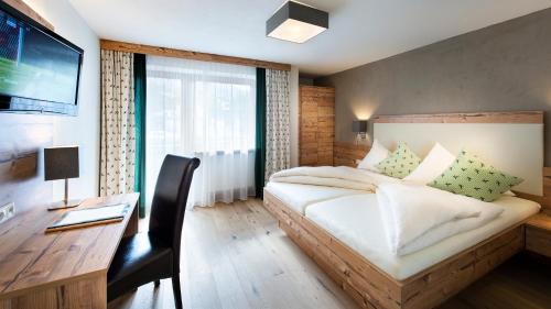 a bedroom with a bed and a desk with a computer at Hotel Hubertushof in Lermoos