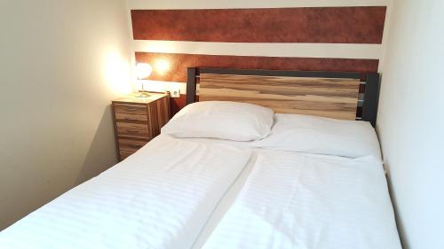 a bedroom with two white beds and a wooden headboard at Gasthof Paradiesgartl in Kleinpöchlarn