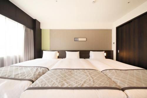 a bedroom with two beds with white sheets at Richmond Hotel Higashi Osaka in Osaka