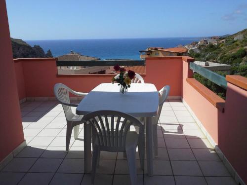a white table and chairs on a balcony with the ocean at Appartamento Panoramico con due terrazze vista sul mare - IUN P5019 in Buggerru