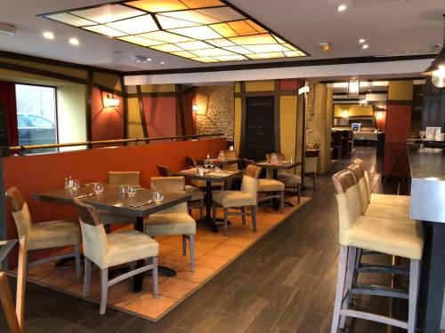 a restaurant with tables and chairs and a bar at The Originals City, Hôtel Le Coeur d'Or, Sedan Est in Douzy