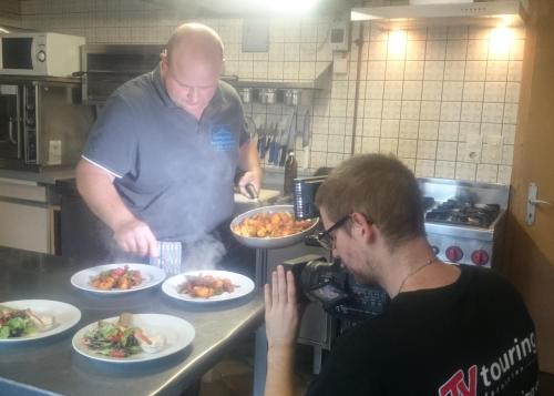 a man taking a picture of a man preparing food in a kitchen at Landgasthof und Pension Zum löwen in Bischofsheim an der Rhön
