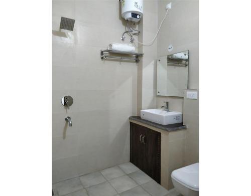 a bathroom with a sink and a toilet and a mirror at Hotel Divya in Rishīkesh