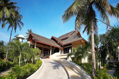 a house with palm trees in front of it at Chada Lanta Beach Resort - SHA Extra Plus in Ko Lanta