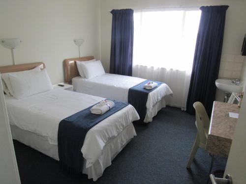 a hotel room with two beds and a window at Concord Christian Guesthouse in Durban