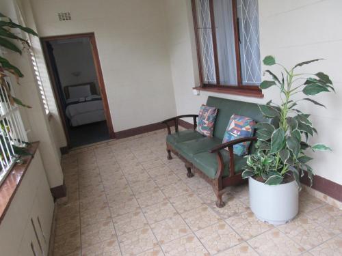 a living room with a green couch and a potted plant at Concord Christian Guesthouse in Durban