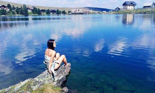 a man sitting on a rock in a lake at Erlebnis - Hütten Falkert by S4Y in Patergassen