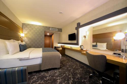 Cette chambre comprend un lit, un bureau et un miroir. dans l'établissement AYMİRA HOTEL & SPA, à Gereniz