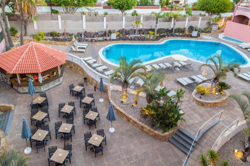 
a patio area with tables, chairs and umbrellas at Marola Park in Playa de las Americas
