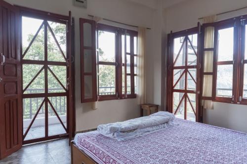 a bedroom with large windows and a bed in a room at Dinesh House in Pokhara