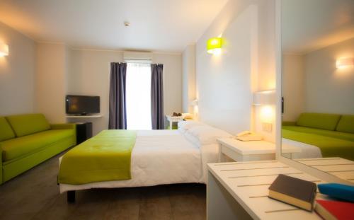 a bedroom with a bed and a couch and a mirror at Hotel Garden Sea Wellness & Spa 4 stelle superior in Caorle