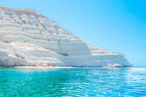 a group of people standing on a beach next to a cliff at Beatus Suites And Rooms B&B in Canicattì