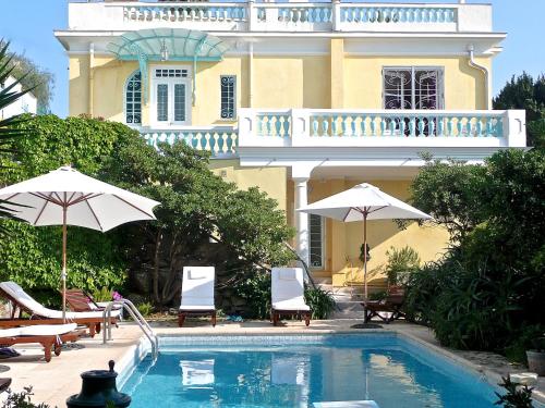 - une piscine avec des chaises et des parasols en face d'une maison dans l'établissement Villa Dracoena, à Nice