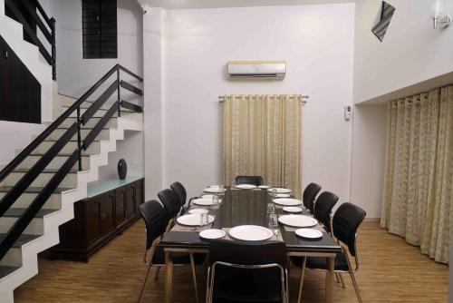 a room with a long table with chairs and a staircase at ShreeVilla Corporate Guest House in Nashik
