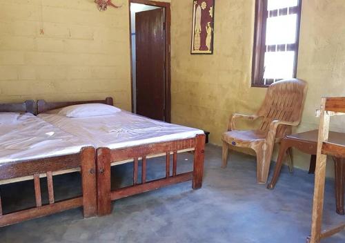 a bedroom with two beds and a chair in it at Ganesh Gate in Pottuvil