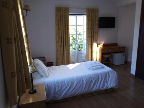 a bedroom with a white bed and a window at Residencial Gil Vicente in Sardoal