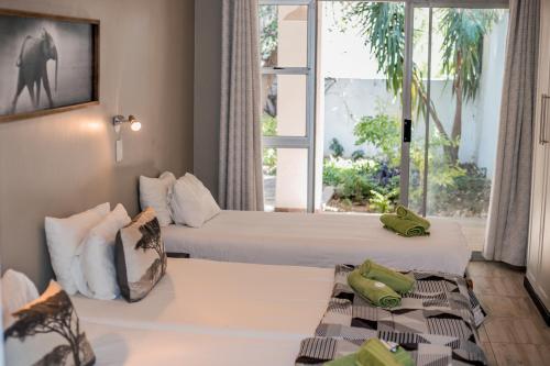 um quarto de hotel com duas camas e uma janela em Out of Africa Guesthouse em Otjiwarongo
