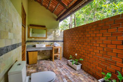 a bathroom with a toilet and a brick wall at Azura Resort in Phu Quoc