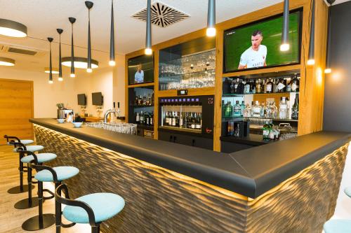 a bar with stools and a tv on the wall at Hotel Schönbuch in Pliezhausen