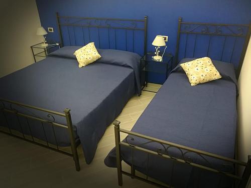 twee bedden in een slaapkamer met blauwe muren bij U dammusu ra cianta in Modica