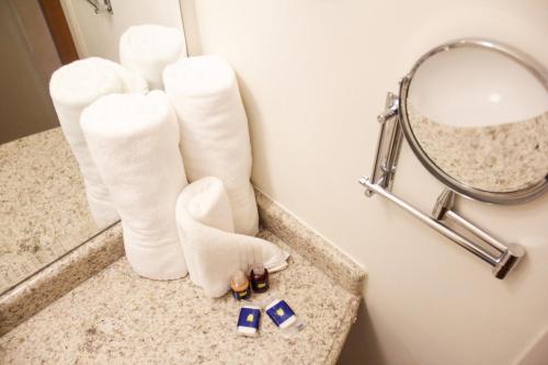 a hotel bathroom with white boots and a mirror at Hotel City Hall in São José dos Campos