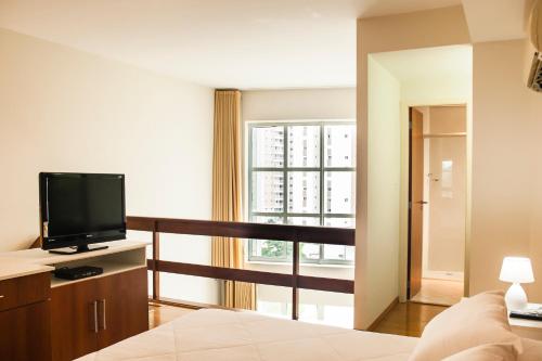 a bedroom with a bed and a tv and a window at Hotel City Hall in São José dos Campos
