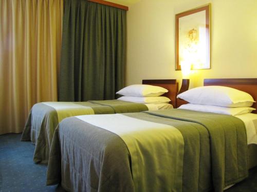 a hotel room with three beds with green blankets at Perla, Resort & Entertainment in Nova Gorica