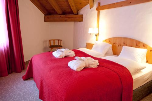 two towels on a bed with a red blanket at Hotel Rosatsch in Pontresina