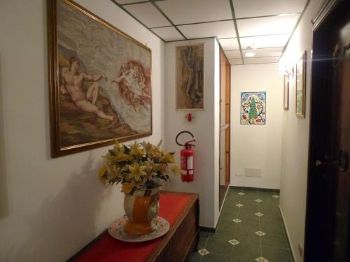 a hallway with a vase of flowers and a painting at Hotel La Riva in Giardini Naxos