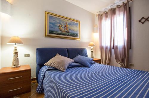 Un dormitorio con una cama azul y una pintura en la pared en La Sartia Apartment, en Porto Pozzo