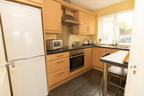 a kitchen with wooden cabinets and a white refrigerator at PondeROSEa Cottage Free Gated Parking M1 & City location, wood stove in Lisburn