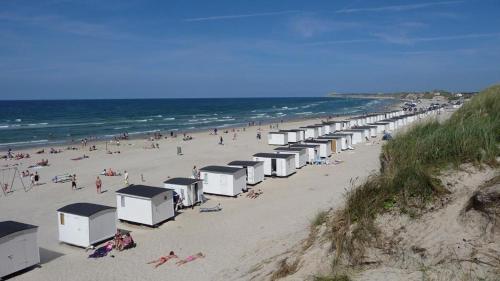 a beach with many beach huts and people on it at Løkken Klit Camping & Cottage Village in Løkken