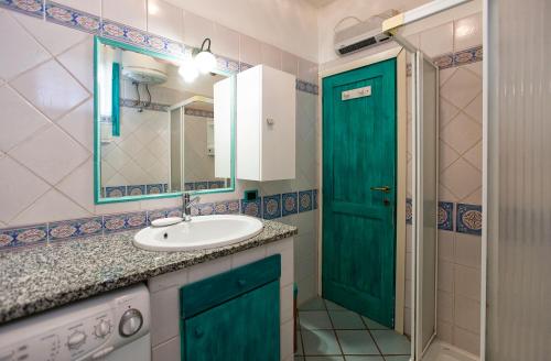 baño con lavabo y puerta verde en La Sartia Apartment, en Porto Pozzo