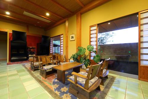 a room with chairs and a table and a large window at Tenjukunomori Keigetsu in Mine