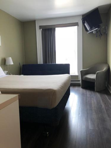 a hotel room with a bed and a chair and a window at Auberge St-Louis in Quebec City