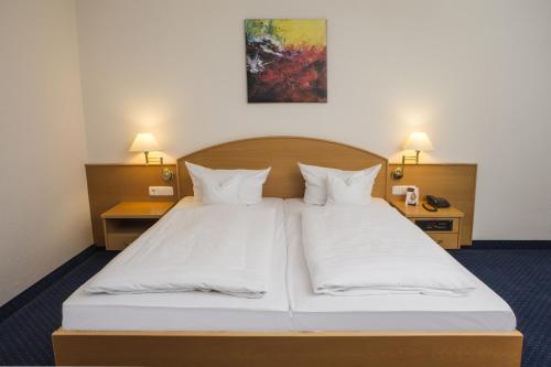 a bedroom with a large white bed with two lamps at Johannesbad Hotel Königshof in Bad Füssing