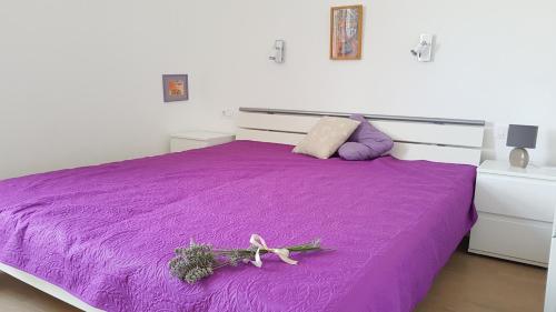 ein violettes Bett mit einer Blume darüber in der Unterkunft Apartman Di in Mali Lošinj