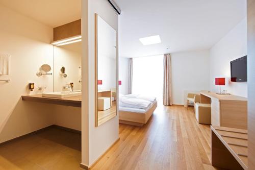 ein Bad mit einem Waschbecken und ein Bett in einem Zimmer in der Unterkunft Sternen Hotel Wolfurt in Bregenz