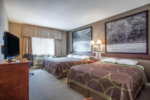 a hotel room with two beds and a flat screen tv at Super 8 by Wyndham Abbotsford BC in Abbotsford