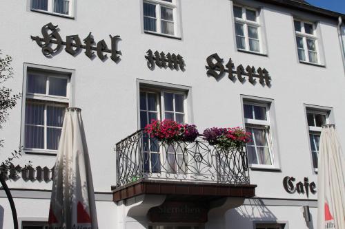 a white building with a balcony with flowers on it at Hotel Zum Stern in Bad Neuenahr-Ahrweiler