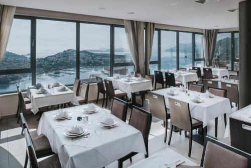 a restaurant with white tables and chairs and windows at Hotel Adria in Dubrovnik