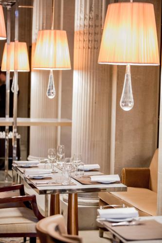 a dining table with wine glasses and lights at Le Meurice – Dorchester Collection in Paris