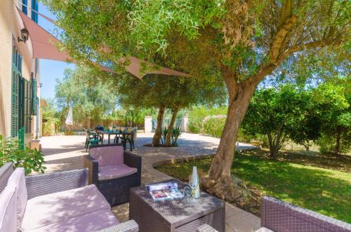 a patio with a table and chairs under a tree at Hort de Can Bou in Porreres